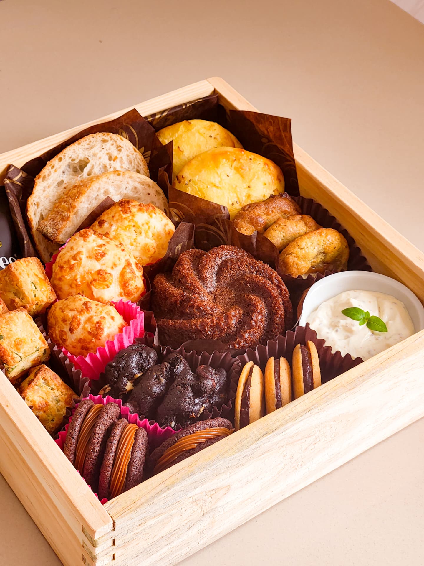 Detalhe da cesta Deli da manhã aberta: pães, mini bolo de chocolate, cookies e ramequim